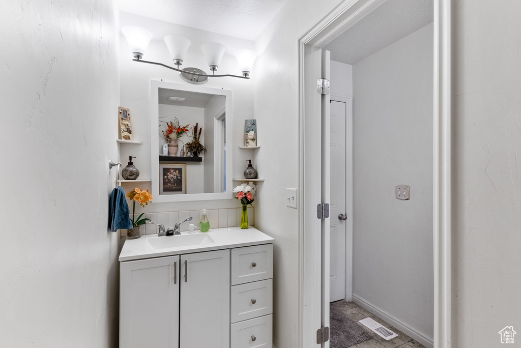 Bathroom featuring tile flooring, oversized vanity, and tasteful backsplash