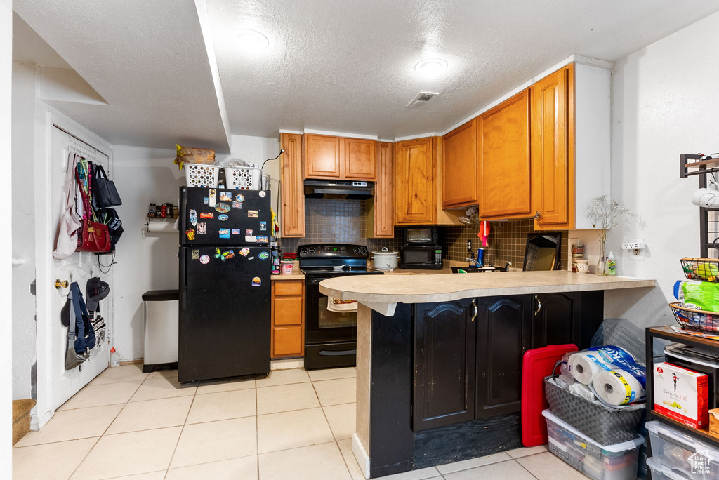 Kitchen with backsplash, kitchen peninsula, light tile floors, and black appliances