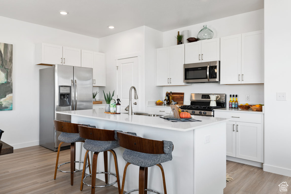 Kitchen featuring a center island with sink, light hardwood / wood-style flooring, a breakfast bar area, and stainless steel appliances