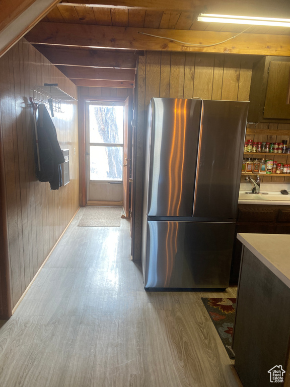 Kitchen with stainless steel fridge, wooden walls, sink, and light hardwood / wood-style flooring