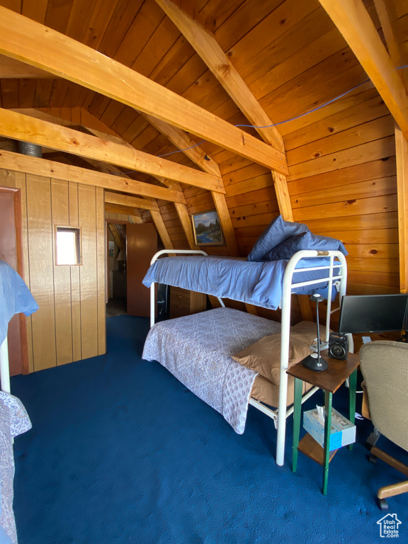 Carpeted bedroom featuring wood walls, wood ceiling, and lofted ceiling with beams