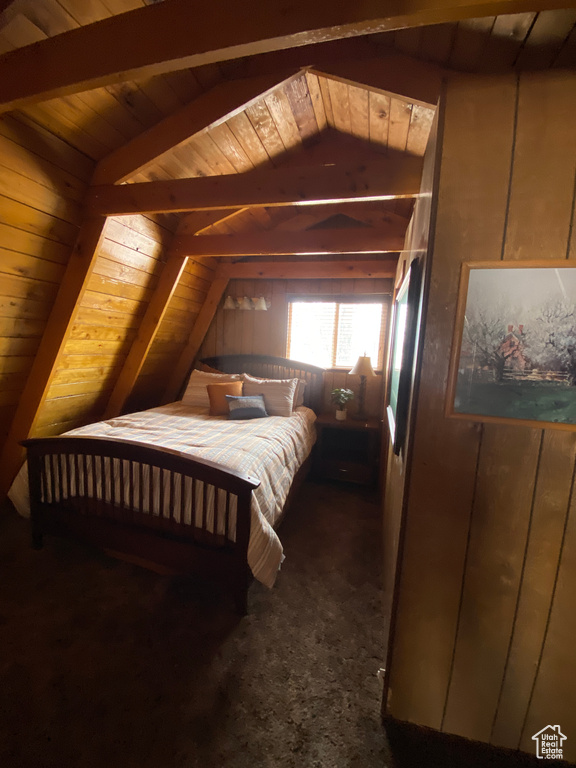 Bedroom with dark carpet, wood walls, wood ceiling, and lofted ceiling with beams