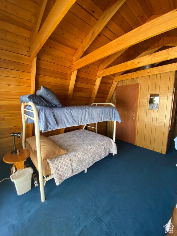Bedroom featuring wood walls, wood ceiling, carpet flooring, and vaulted ceiling with beams
