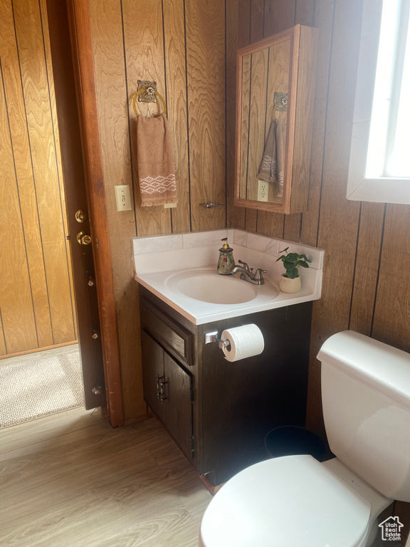 Bathroom featuring vanity, wooden walls, hardwood / wood-style flooring, and toilet