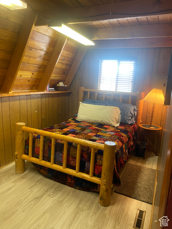 Bedroom featuring light hardwood / wood-style flooring, wood ceiling, wood walls, and lofted ceiling