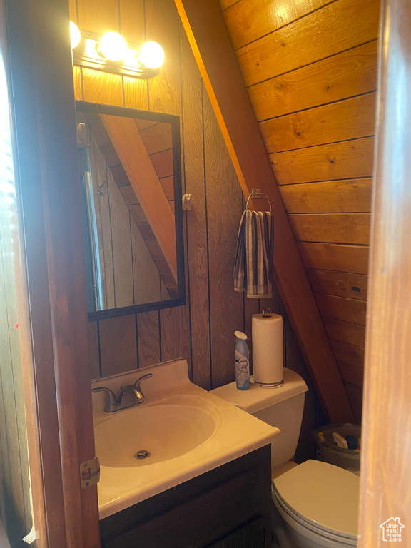 Bathroom featuring wood walls, toilet, vaulted ceiling, and wooden ceiling
