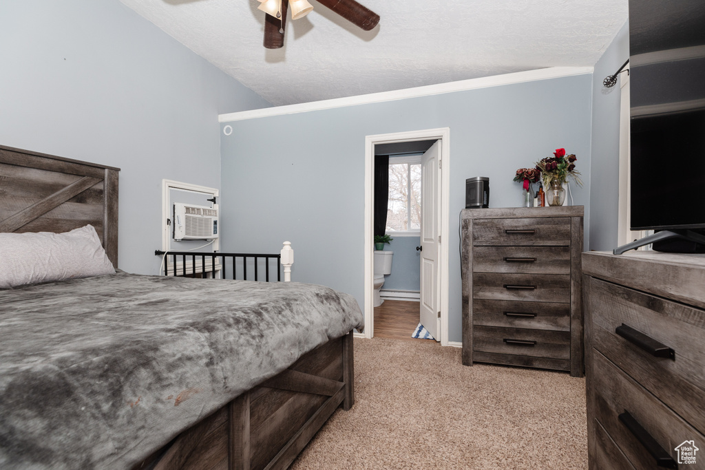 Carpeted bedroom with ensuite bath, lofted ceiling, a wall mounted AC, and ceiling fan