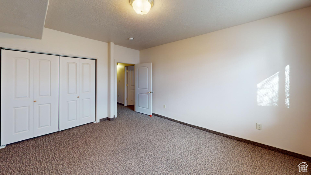 Unfurnished bedroom featuring a closet and dark carpet