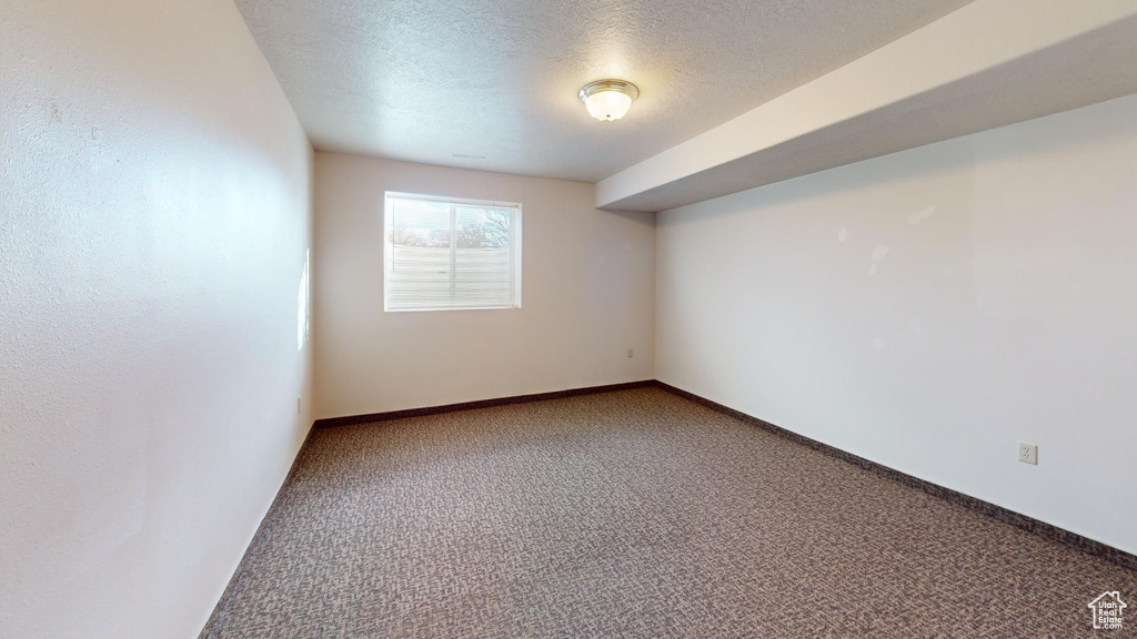 Empty room with a textured ceiling and carpet floors