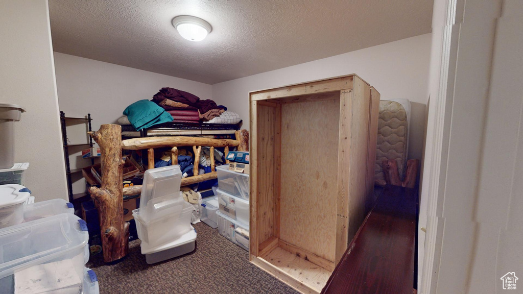 Bedroom with a textured ceiling and dark colored carpet