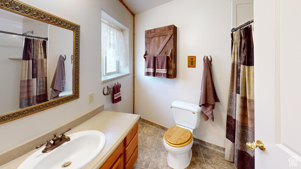 Bathroom with toilet, vanity, and tile flooring