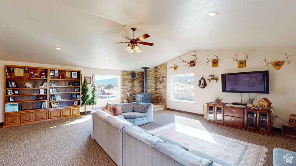 Living room with light colored carpet, a healthy amount of sunlight, vaulted ceiling, and a wood stove