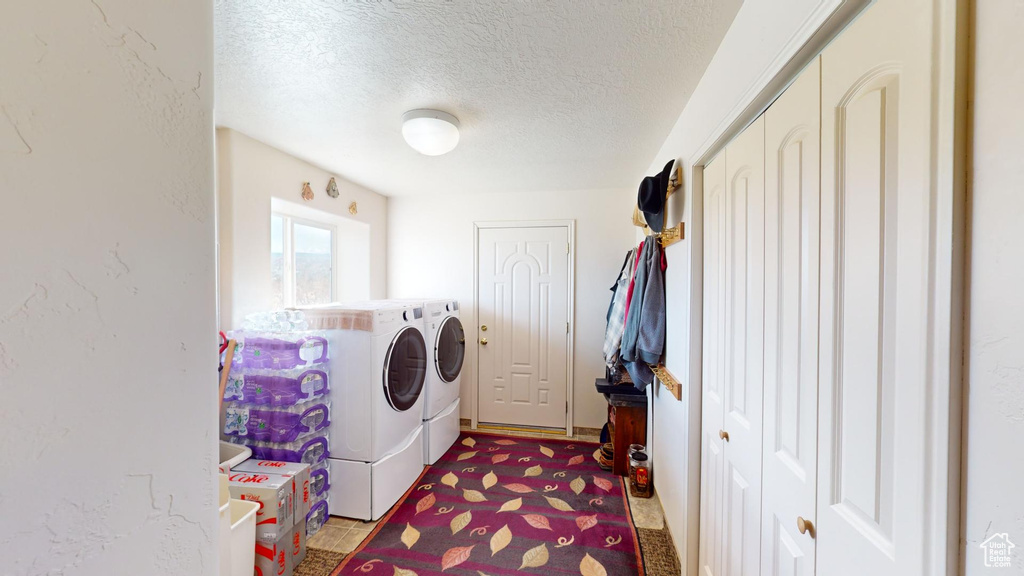 Laundry room featuring a textured ceiling and washer and clothes dryer