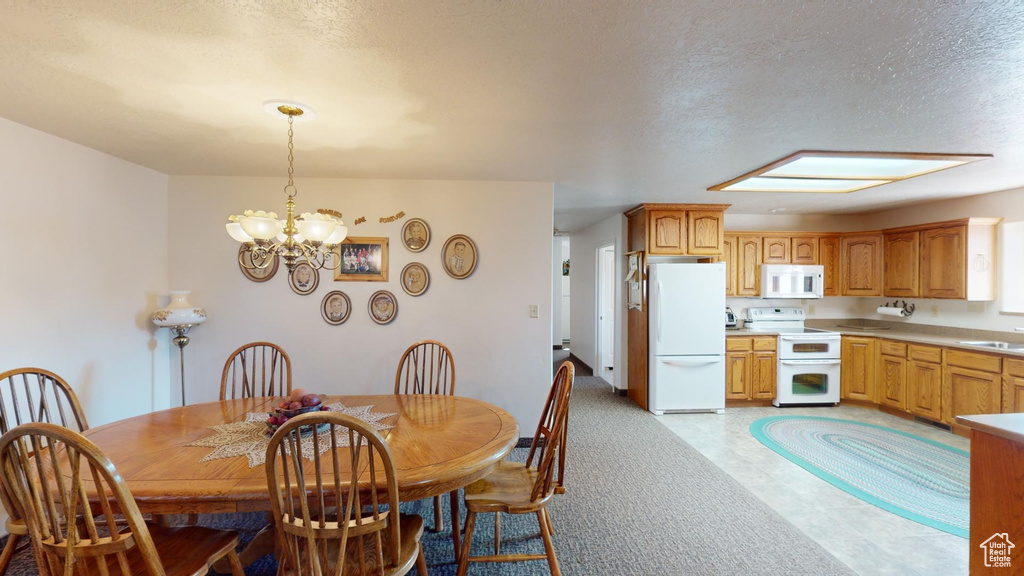 Tiled dining room with a textured ceiling, a skylight, sink, and a chandelier