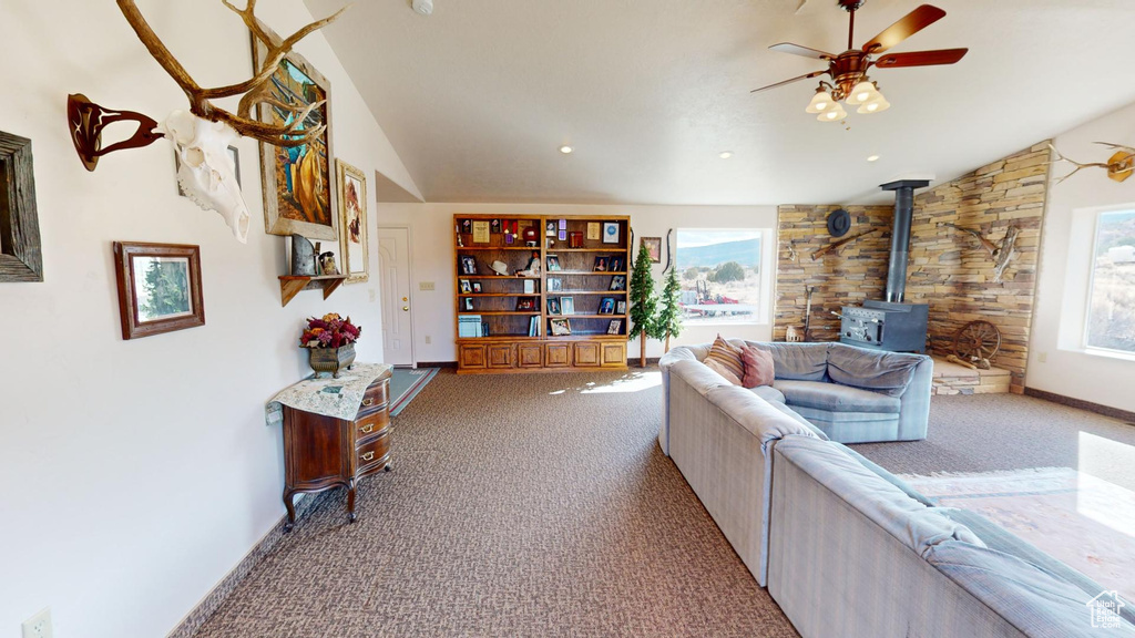 Living room featuring light carpet, a healthy amount of sunlight, ceiling fan, and a wood stove