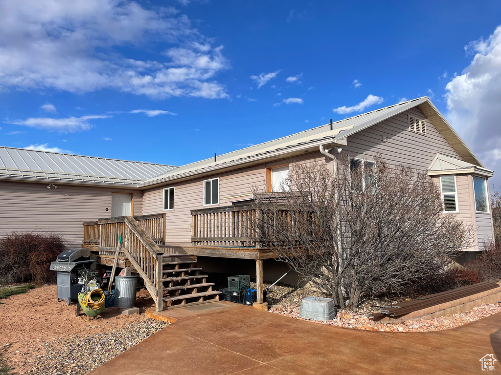 Back of property featuring a wooden deck and a patio area