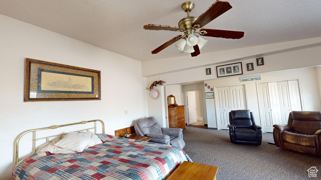 Bedroom with dark carpet, ceiling fan, and two closets