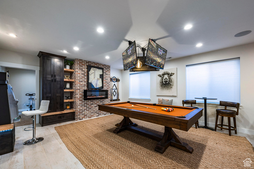 Recreation room featuring brick wall, a fireplace, pool table, and light wood-type flooring