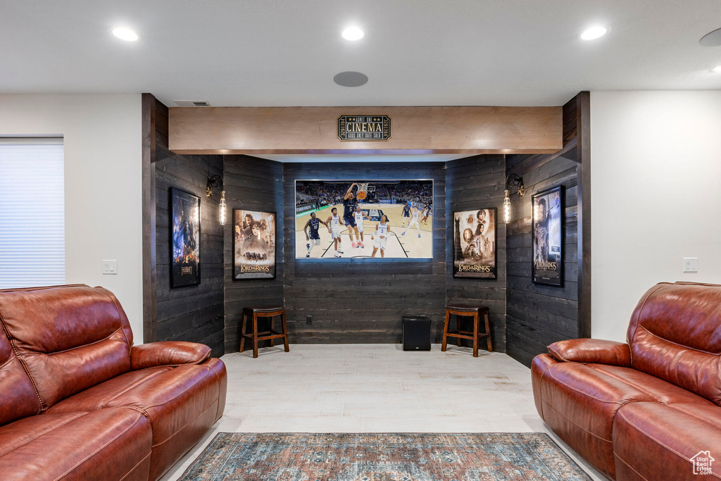 Home theater with wooden walls, beamed ceiling, and light wood-type flooring