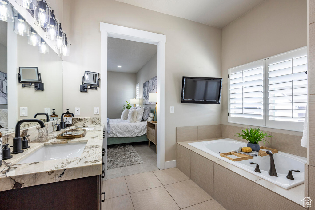 Bathroom featuring tile flooring, dual vanity, and tiled tub