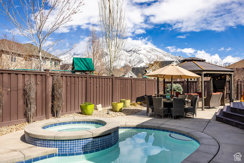 View of pool featuring a mountain view, a gazebo, an in ground hot tub, and a patio area