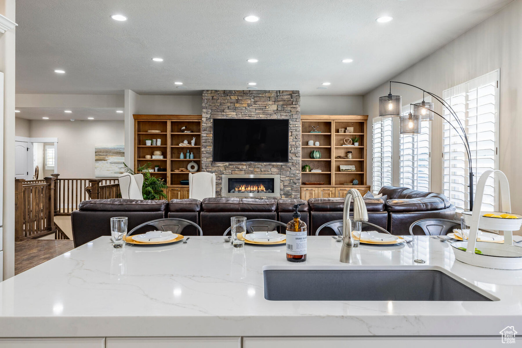 Kitchen featuring plenty of natural light, a stone fireplace, and light stone counters