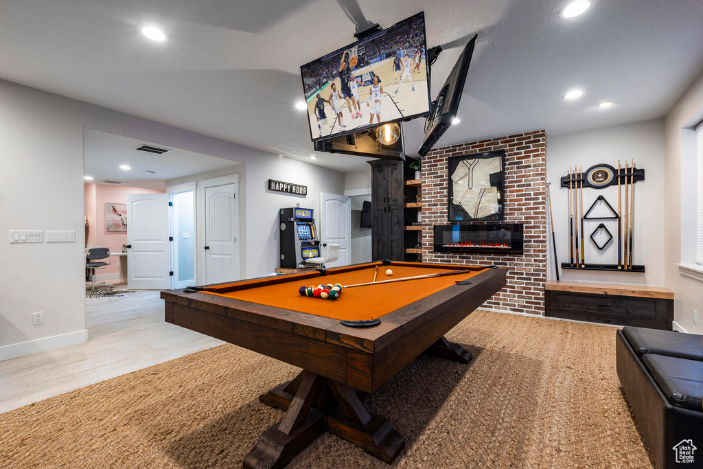 Game room featuring brick wall, billiards, a brick fireplace, and light hardwood / wood-style flooring