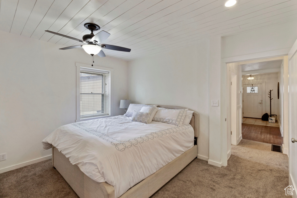 Bedroom featuring wood ceiling, ceiling fan, and dark colored carpet