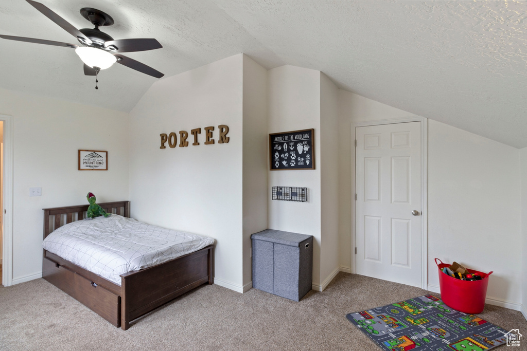 Carpeted bedroom with vaulted ceiling, ceiling fan, and a textured ceiling