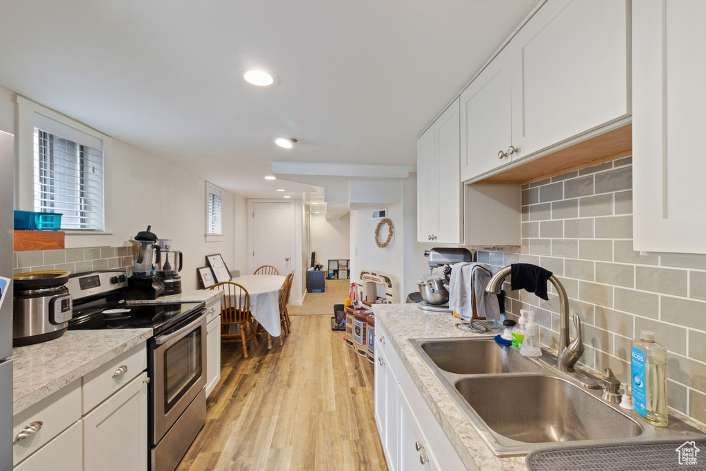 Kitchen featuring white cabinetry, electric range, and light hardwood / wood-style flooring