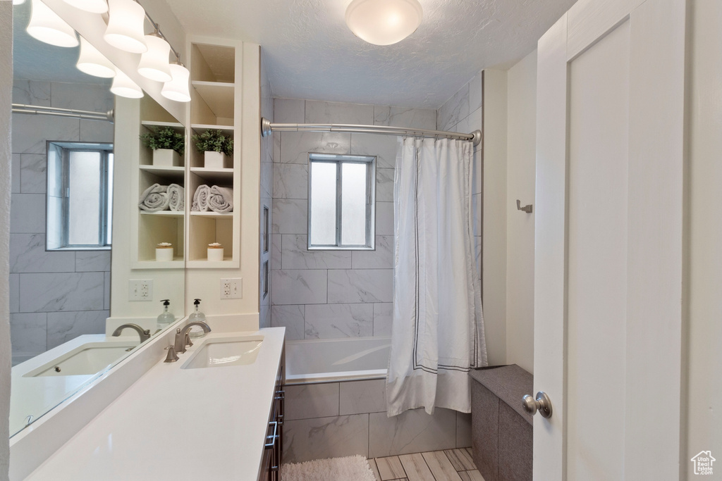 Bathroom featuring shower / bath combination with curtain, a textured ceiling, tile flooring, and large vanity