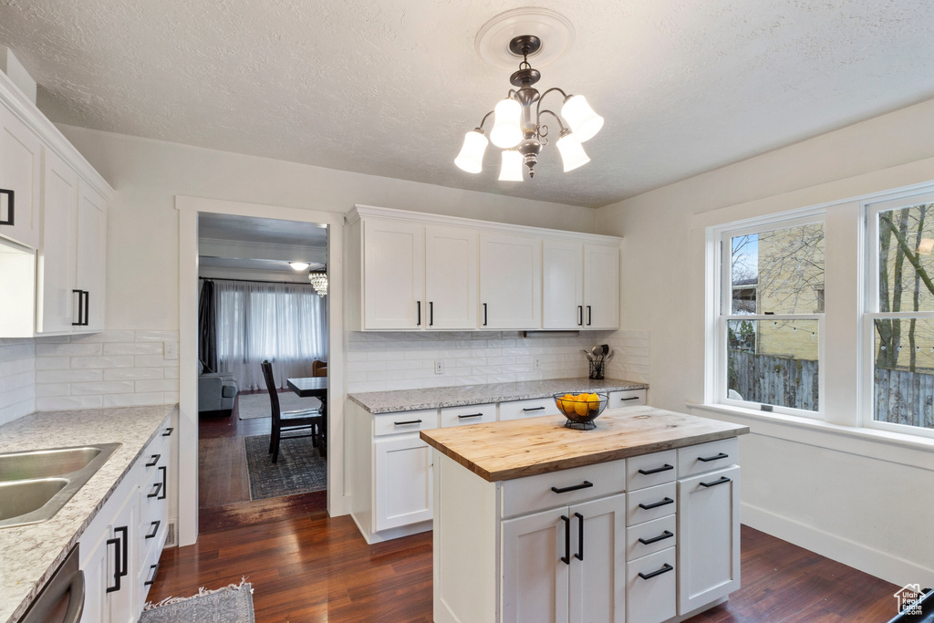Kitchen featuring a notable chandelier, white cabinetry, tasteful backsplash, and dark wood-type flooring