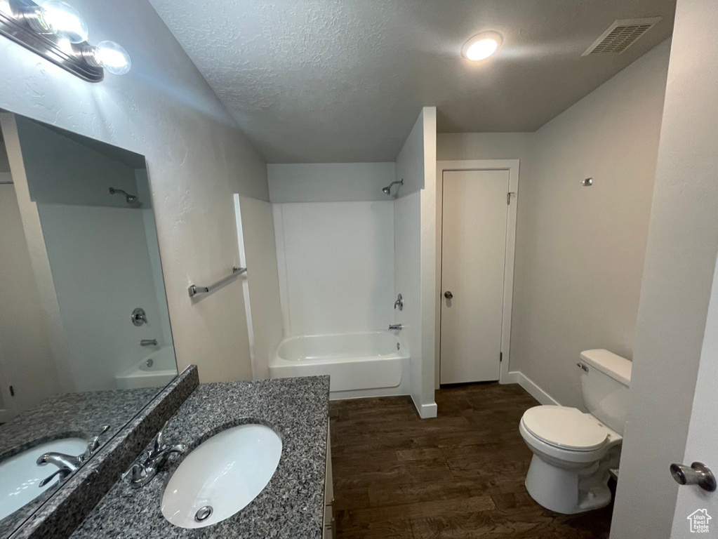 Full bathroom featuring toilet, bathtub / shower combination, vanity, a textured ceiling, and wood-type flooring
