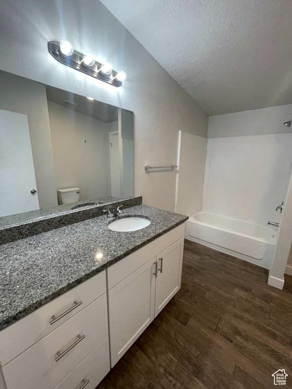 Full bathroom featuring vanity, shower / tub combination, wood-type flooring, a textured ceiling, and toilet