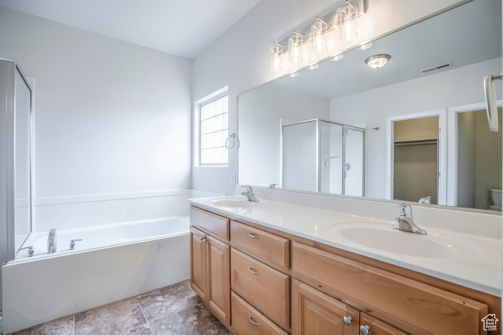 Full bathroom featuring oversized vanity, independent shower and bath, toilet, tile flooring, and dual sinks