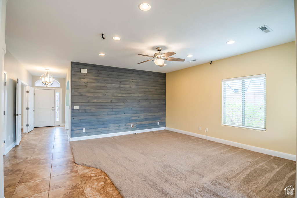 Carpeted spare room featuring wood walls and ceiling fan