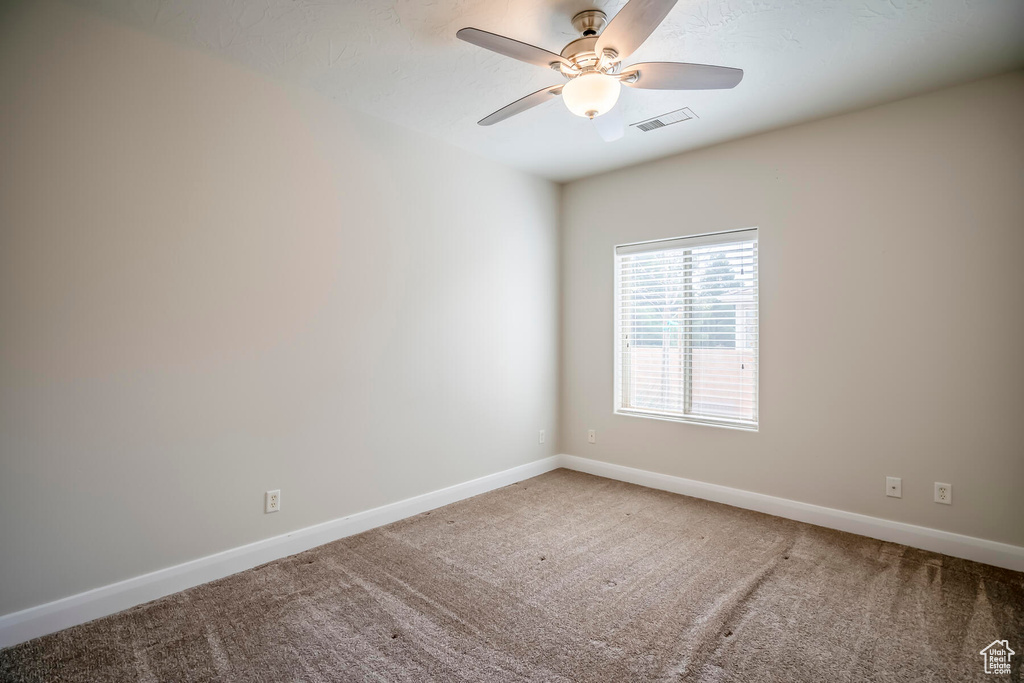 Unfurnished room featuring ceiling fan and carpet