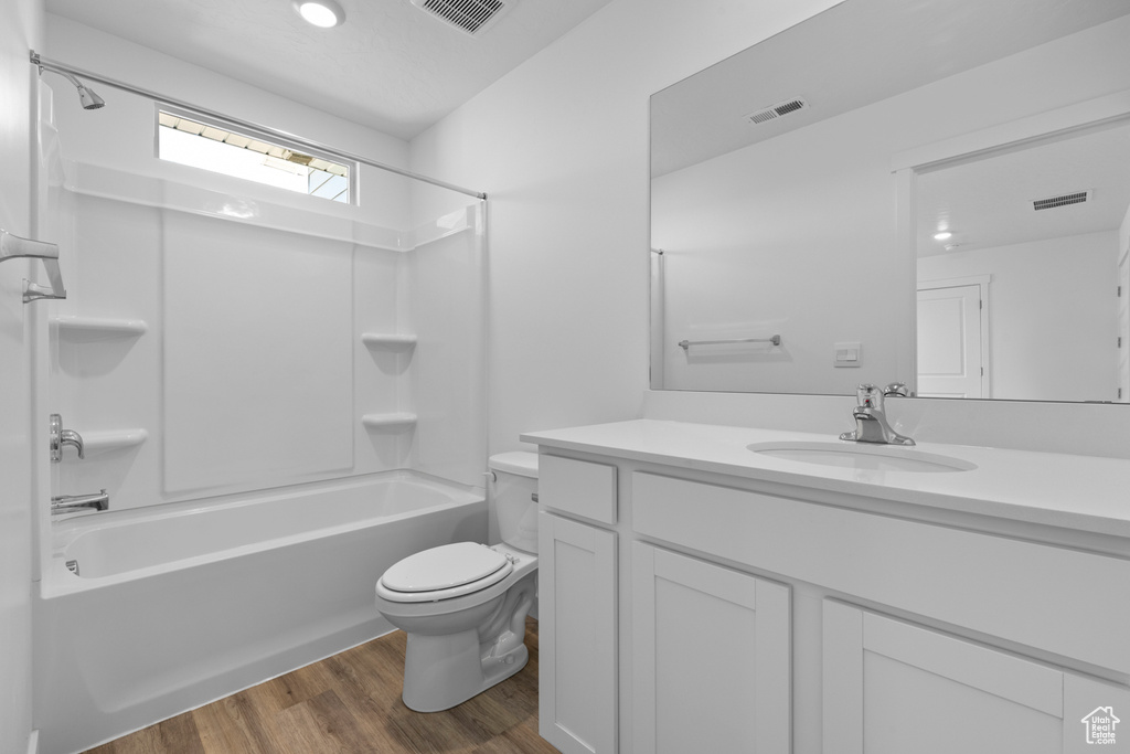 Full bathroom featuring shower / bathtub combination, large vanity, hardwood / wood-style floors, and toilet