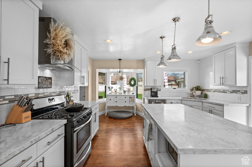 Kitchen featuring white cabinets, dark hardwood / wood-style floors, hanging light fixtures, and gas stove