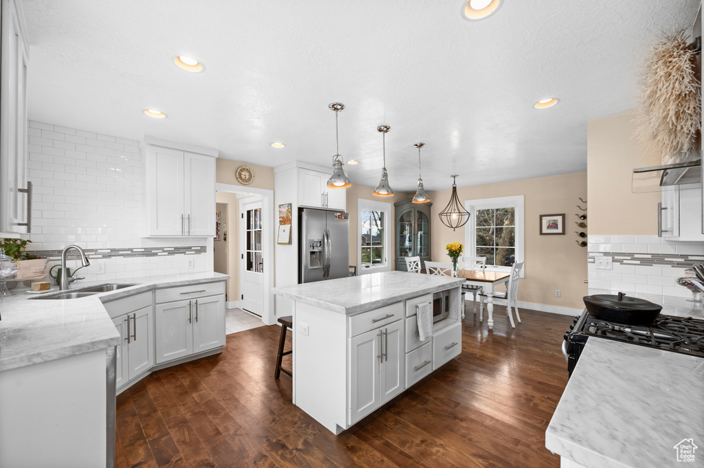 Kitchen with backsplash, dark hardwood / wood-style floors, stainless steel fridge, and white cabinets