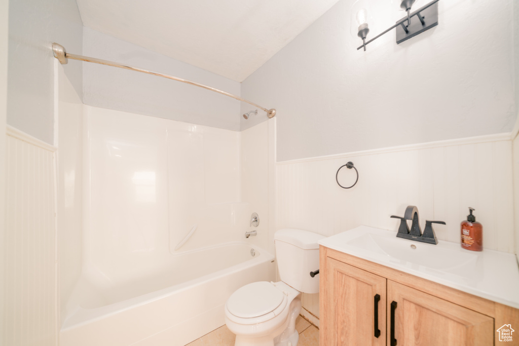 Full bathroom with toilet, vaulted ceiling, tile flooring, vanity, and bathtub / shower combination
