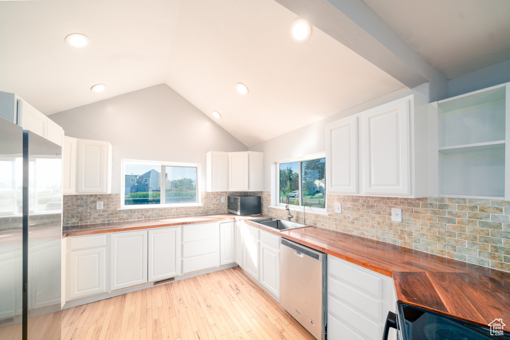 Kitchen with white cabinetry, light hardwood / wood-style floors, wood counters, dishwasher, and tasteful backsplash