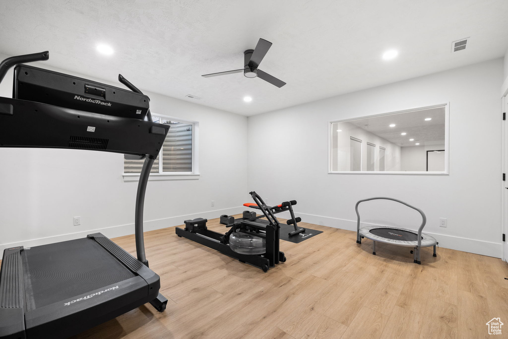 Exercise room with ceiling fan and light hardwood / wood-style flooring