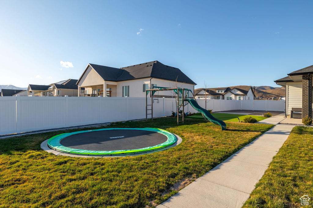 View of yard with a playground and a trampoline
