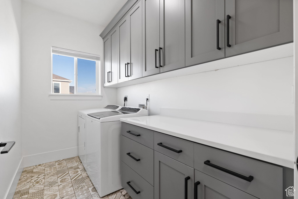 Laundry room featuring light tile floors, electric dryer hookup, cabinets, and separate washer and dryer