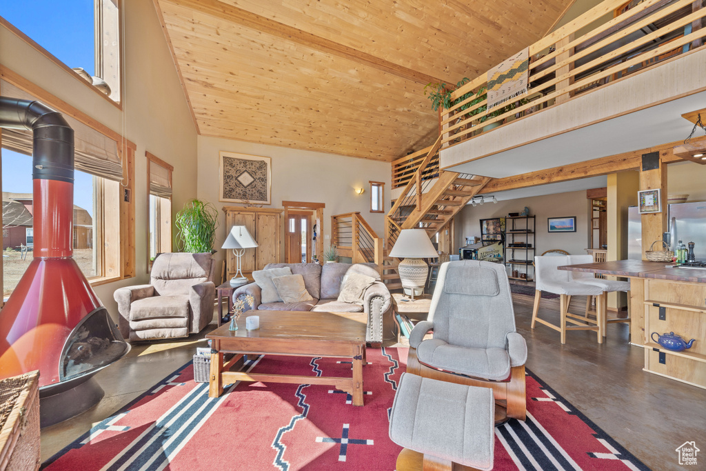 Living room with plenty of natural light, a towering ceiling, wooden ceiling, and a wood stove