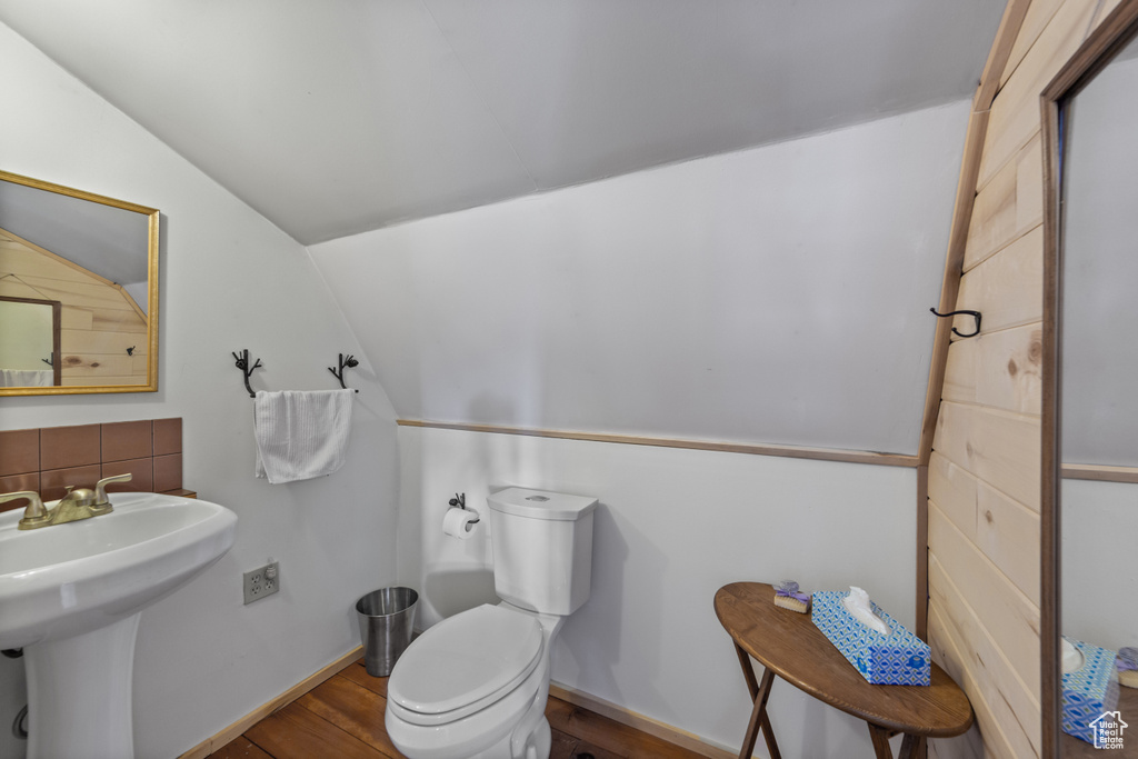 Bathroom with hardwood / wood-style floors, toilet, lofted ceiling, and tasteful backsplash