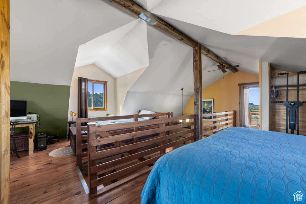 Bedroom with multiple windows, lofted ceiling with beams, and dark hardwood / wood-style floors