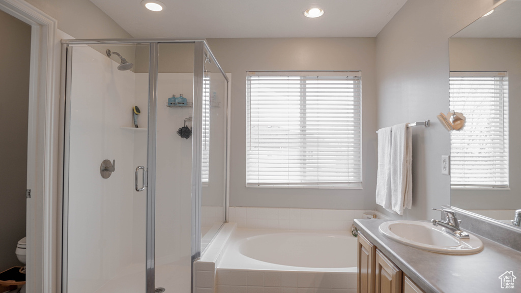 Full bathroom featuring shower with separate bathtub, toilet, and large vanity
