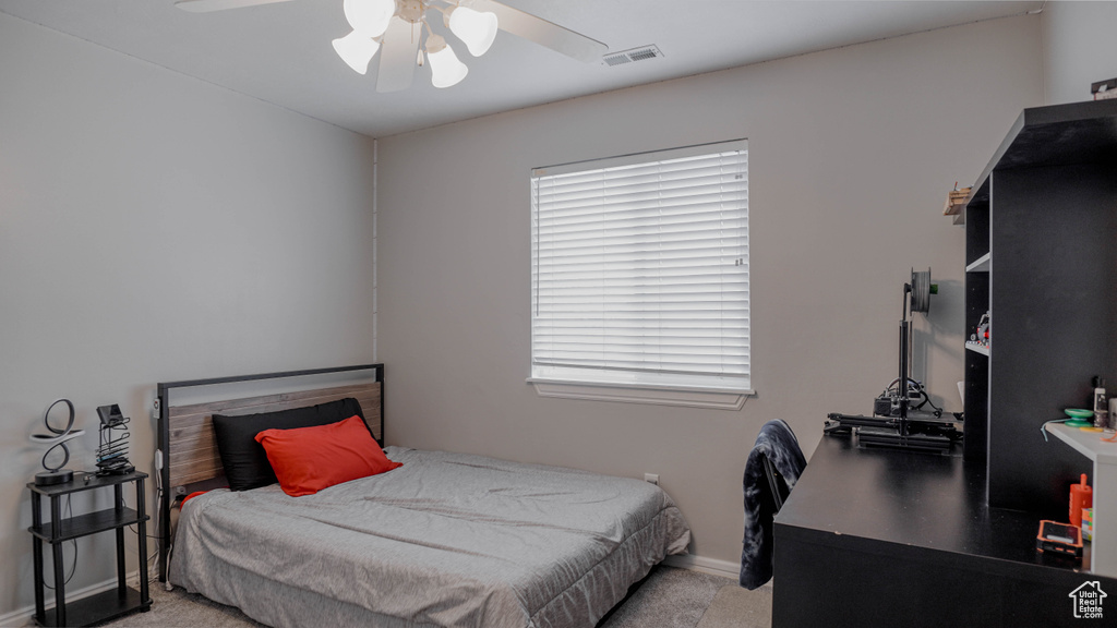 Carpeted bedroom featuring multiple windows and ceiling fan